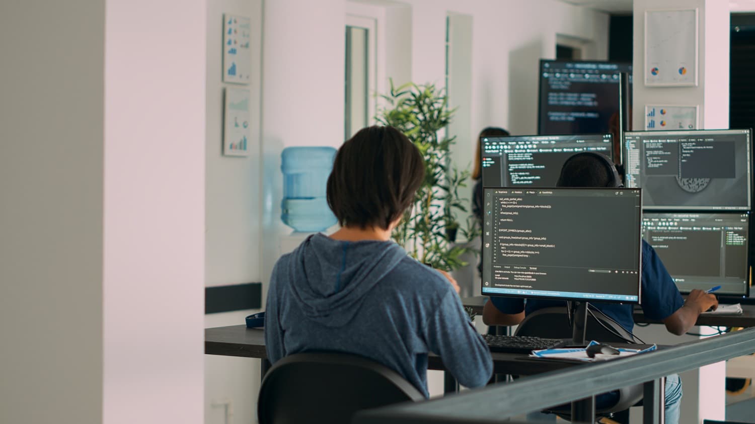 Multiethnic group of programers working on server code to develop new database user interface on computers. IT engineers coding html script with artificial intelligence on terminal window.